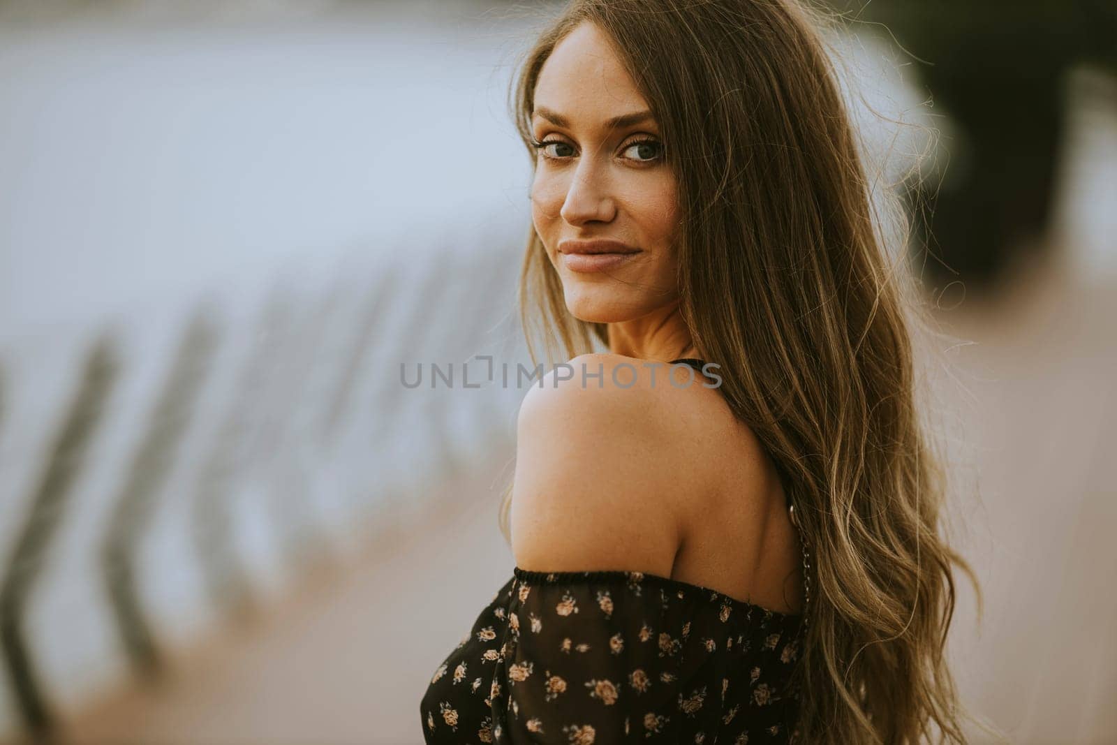 Pretty young long hair brunette woman walking on the riverside