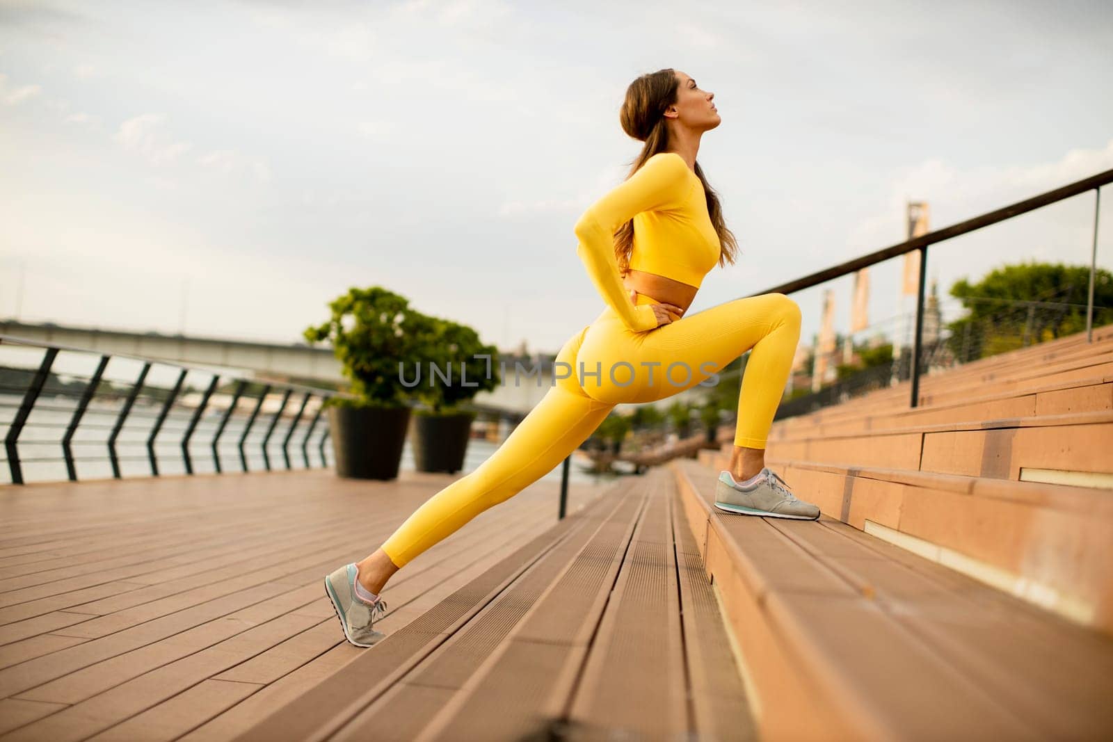 Beautiful young woman stretching on the riverside