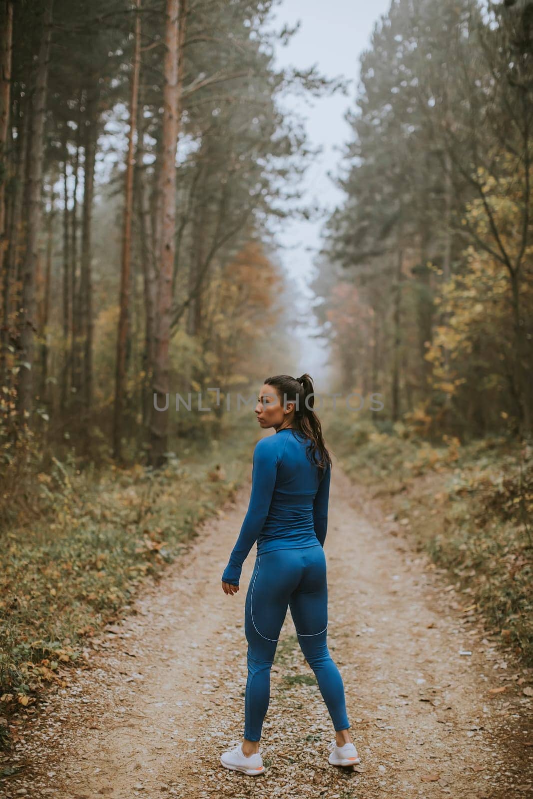 Pretty young woman take a break during outdoor exercise on the forest trail at autumn