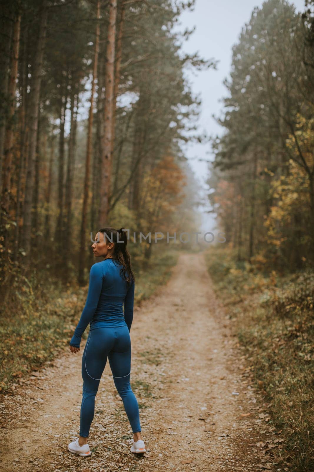 Pretty young woman take a break during outdoor exercise on the forest trail at autumn