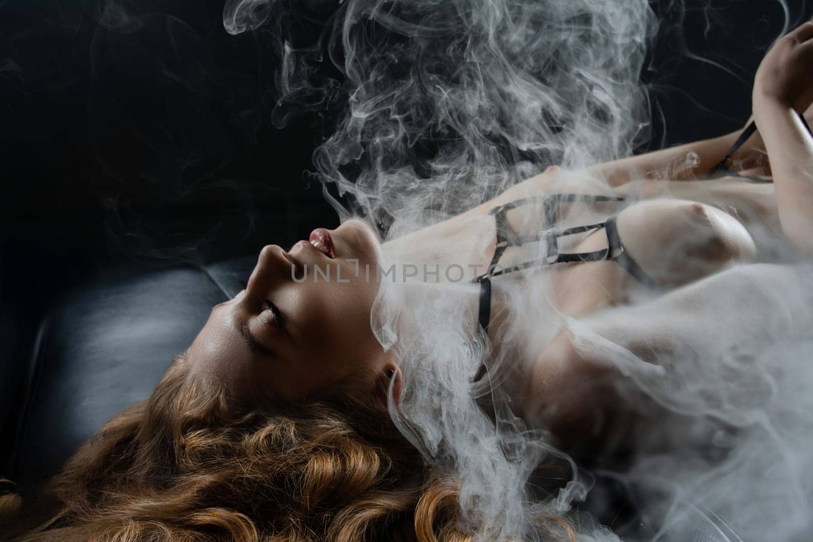 A confident woman exudes sensuality and grace, enveloped in soft smoke, celebrating femininity.