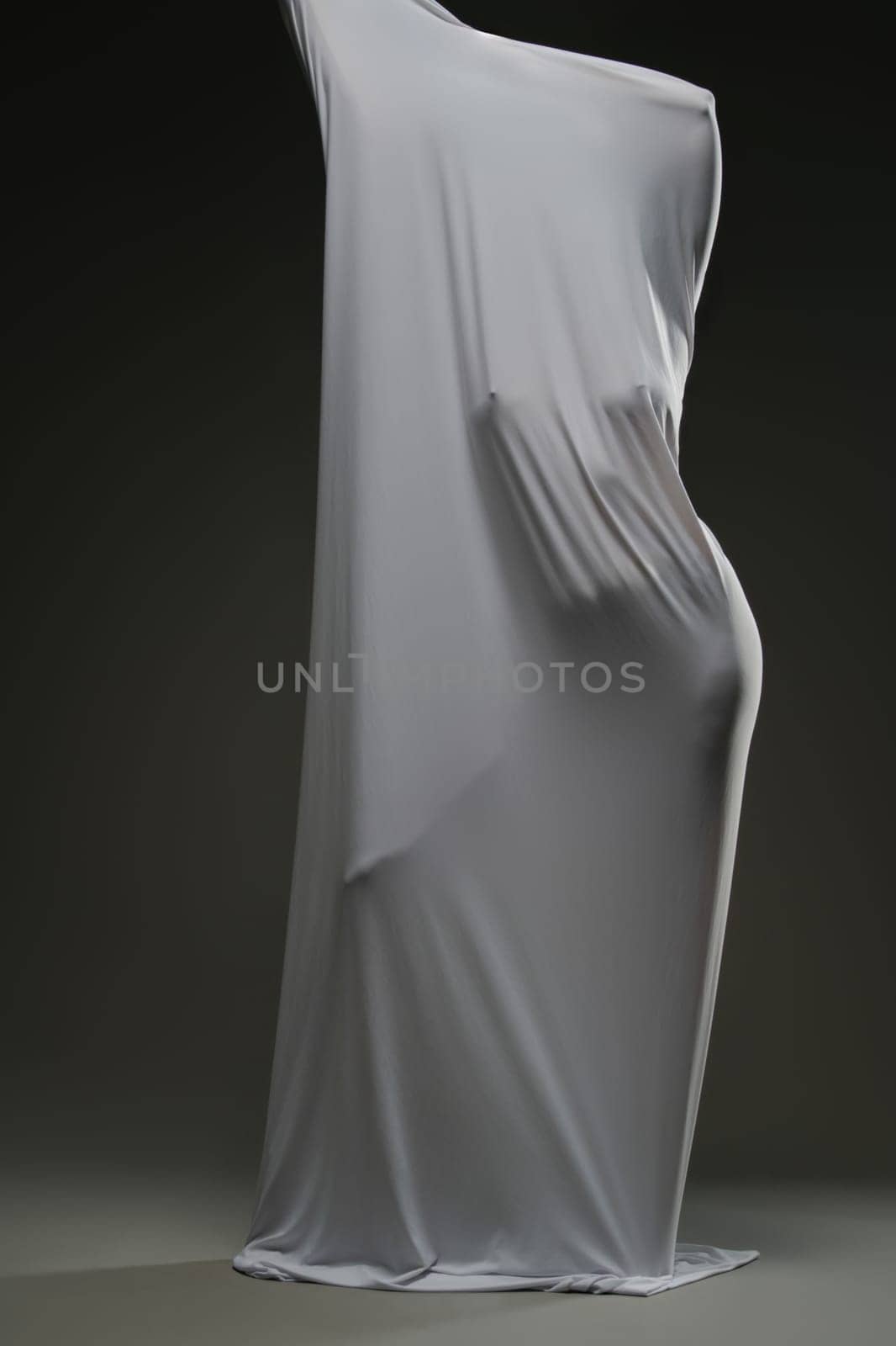 A woman poses gracefully, her beauty accentuated by soft draping fabric that highlights her figure.