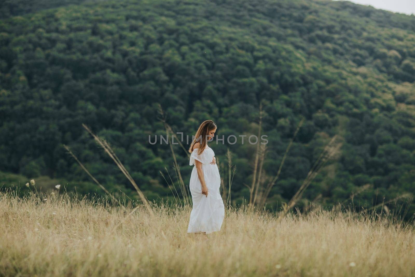 Young pregnant woman relaxing outside in nature at summer day