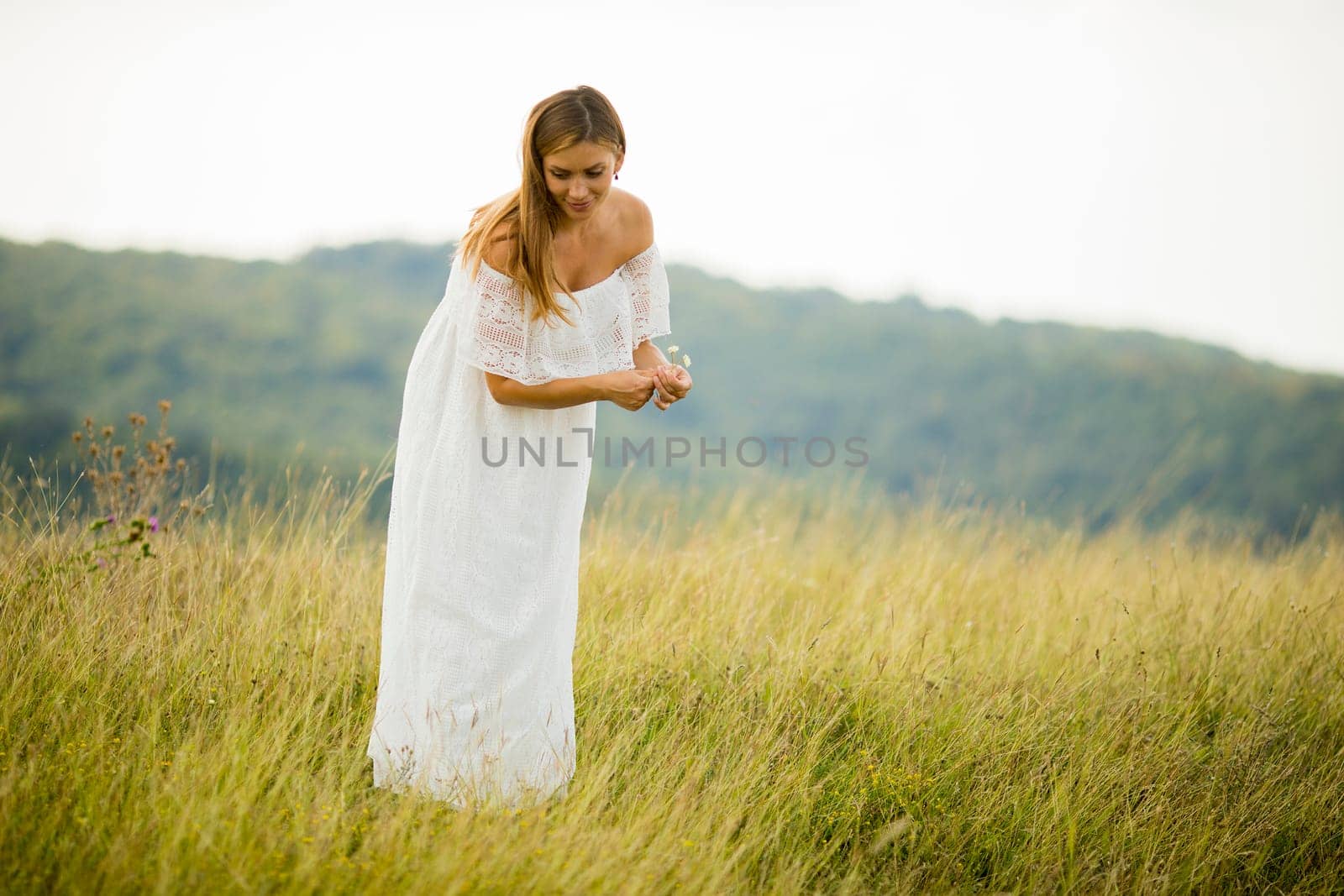 Young pregnant woman relaxing outside in nature at summer day