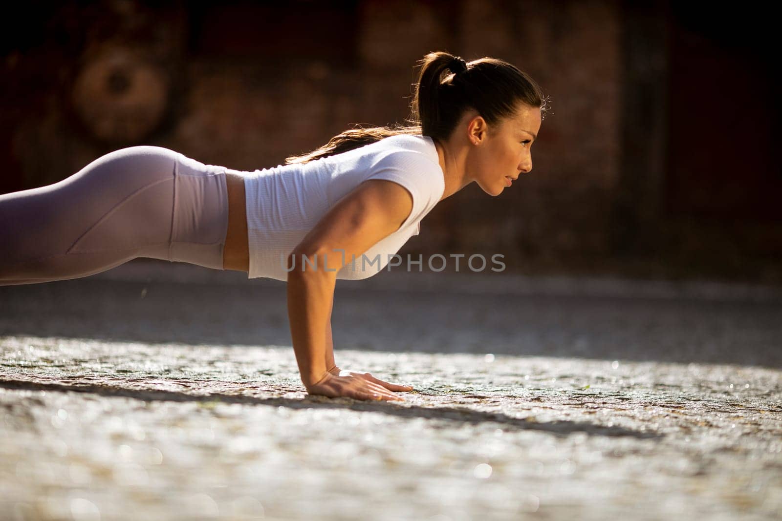 Pretty young woman doing puhsups on the street