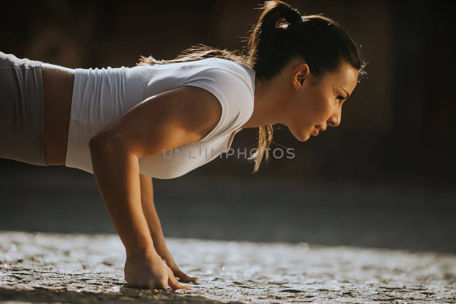 Pretty young woman doing puhsups on the street