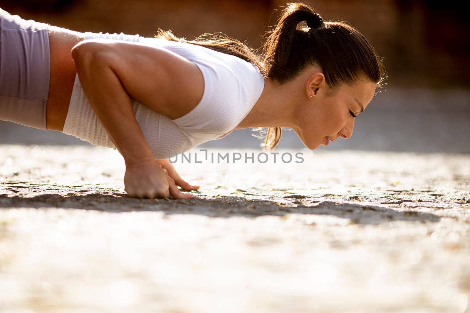 Pretty young woman doing puhsups on the street