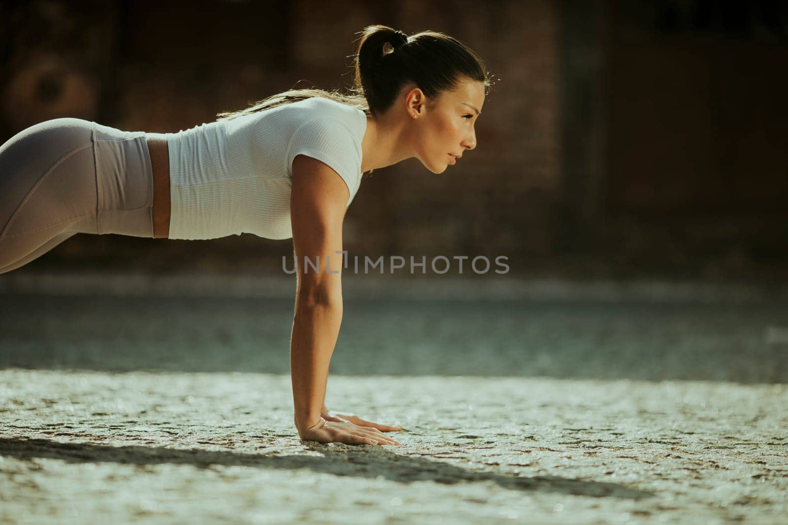 Pretty young woman doing puhsups on the street
