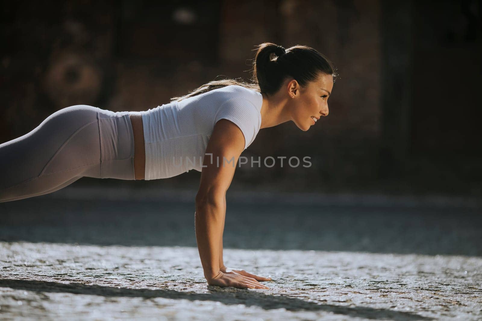 Pretty young woman doing puhsups on the street