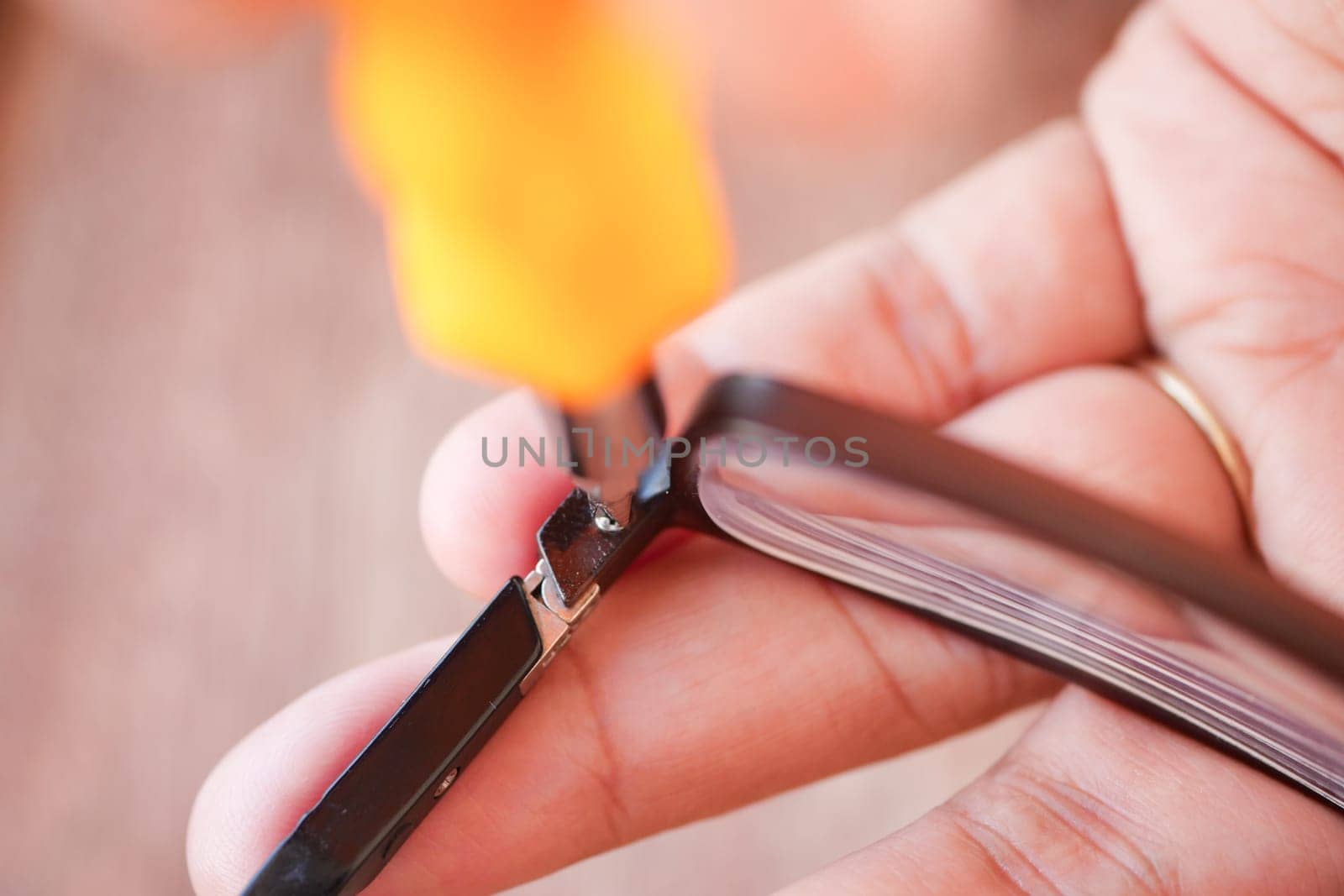 A person is fixing eyeglasses using a screwdriver in a bright area.