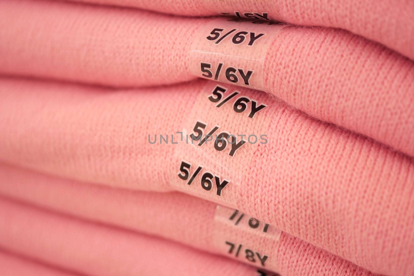 Soft pink garments labeled for toddler sizes are neatly arranged in stacks.
