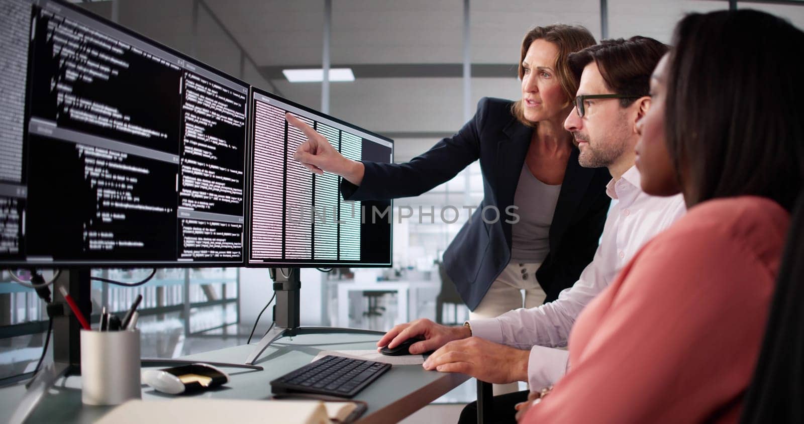 Busy professionals work together on diverse software coding projects in office.