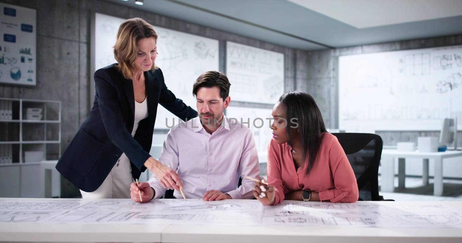Group of Engineers Reviewing Blueprints for Industrial Machine Development Project