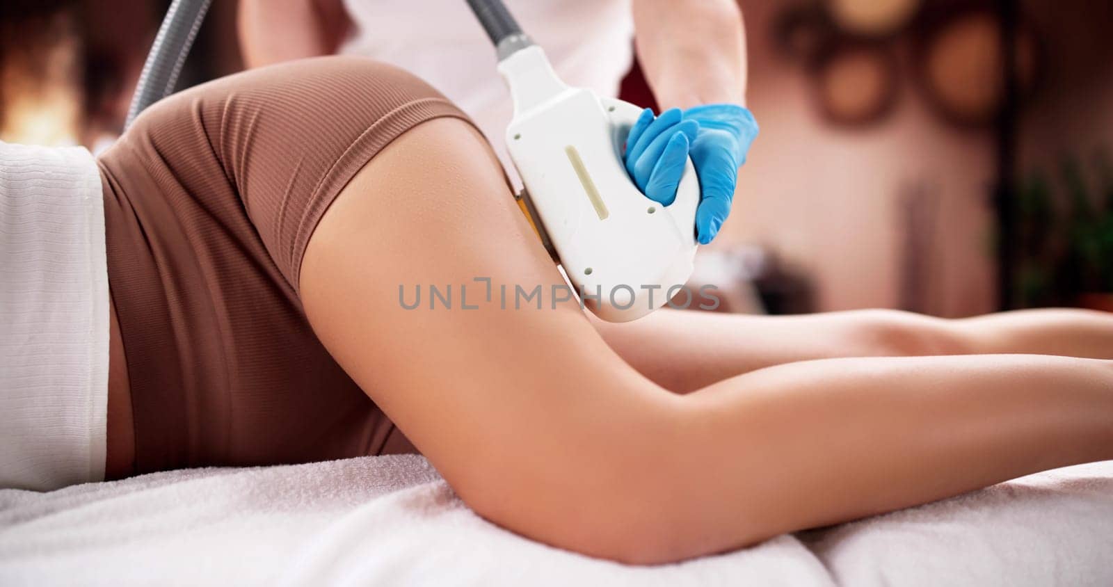 Woman receiving laser hair removal treatment at spa by beautician.
