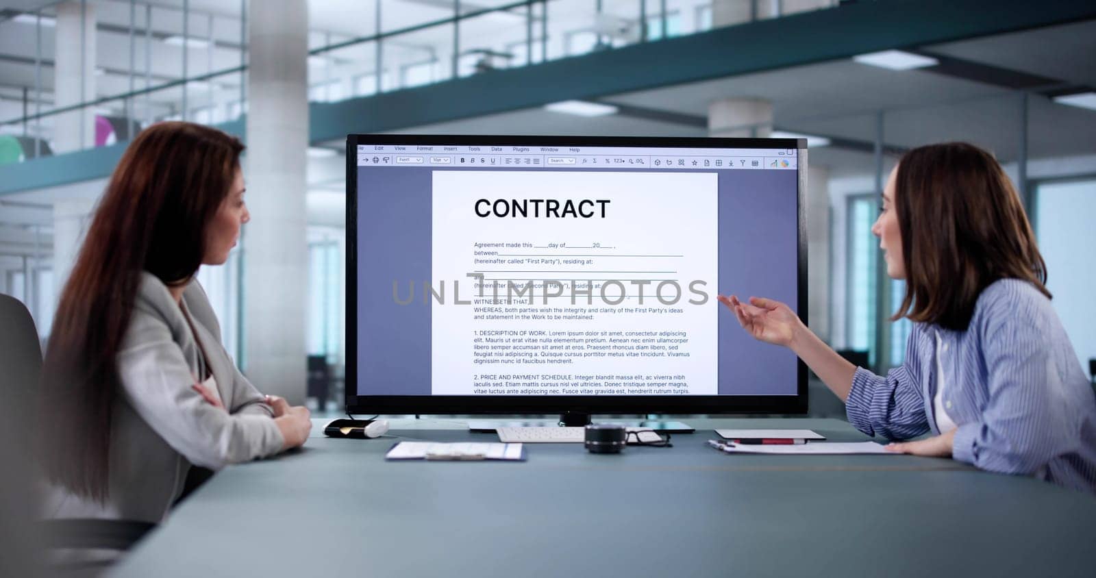 Corporate lawyer assisting female colleague with contract mediation and review.