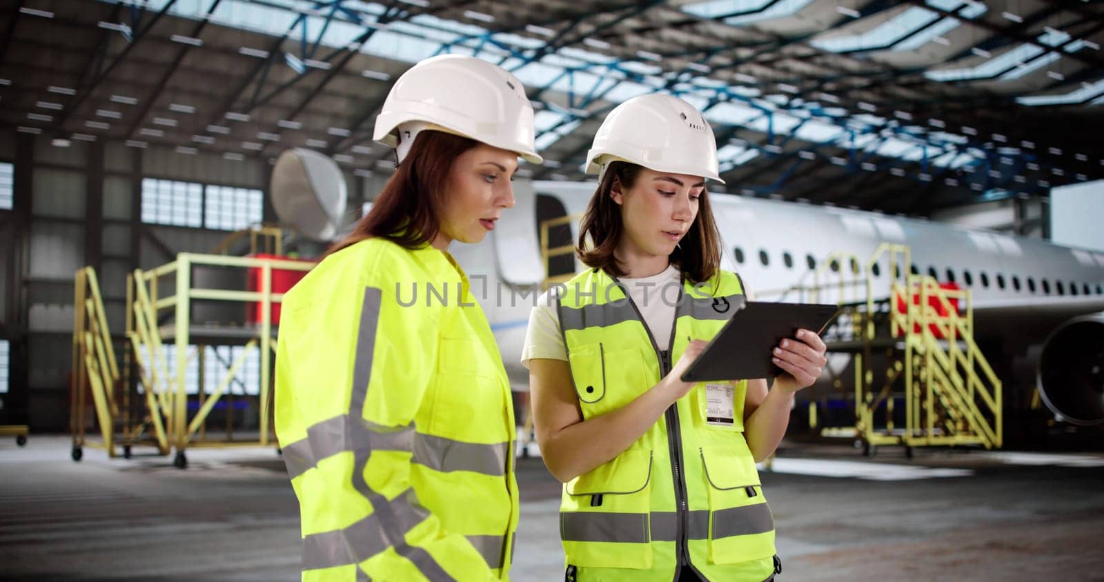 The woman in the hangar checks the jet engine with precision.   The young lady in the aviation industry performs aircraft maintenance.