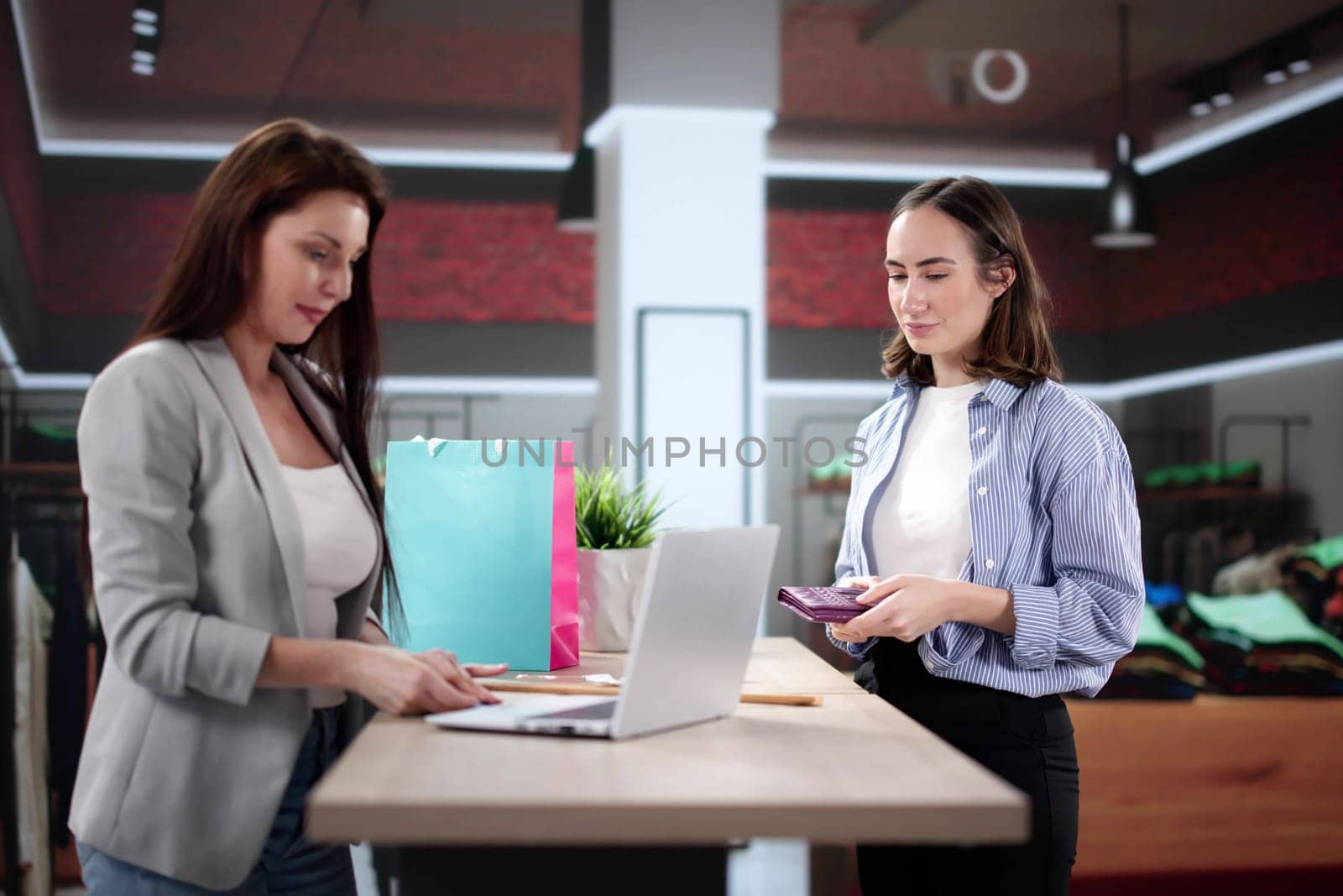 Smiling Retail Assistant Scans Clothes for Happy Customer at Counter.