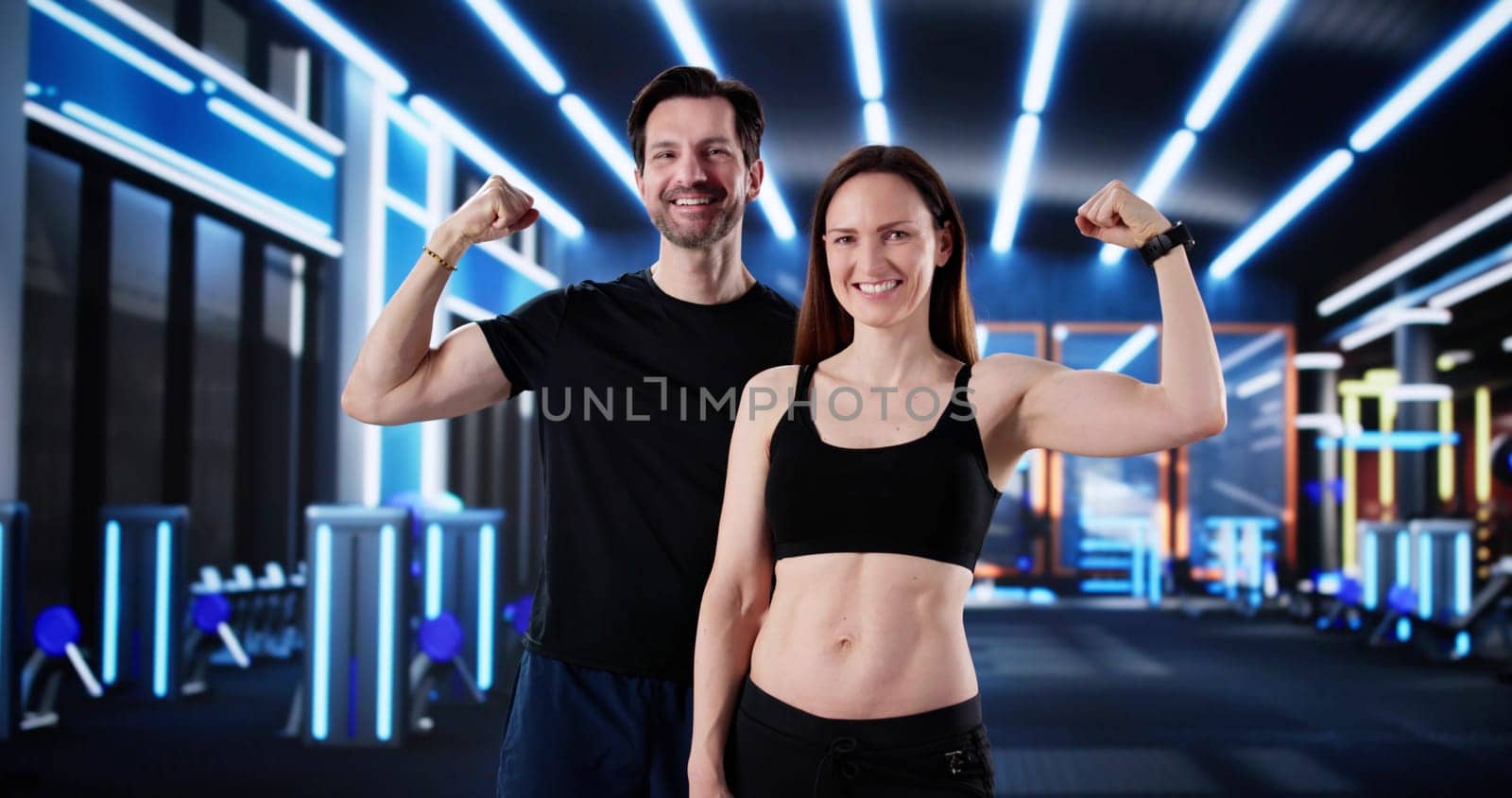 Powerful Personal Trainer and Client Flexing Muscles at Gym Together.