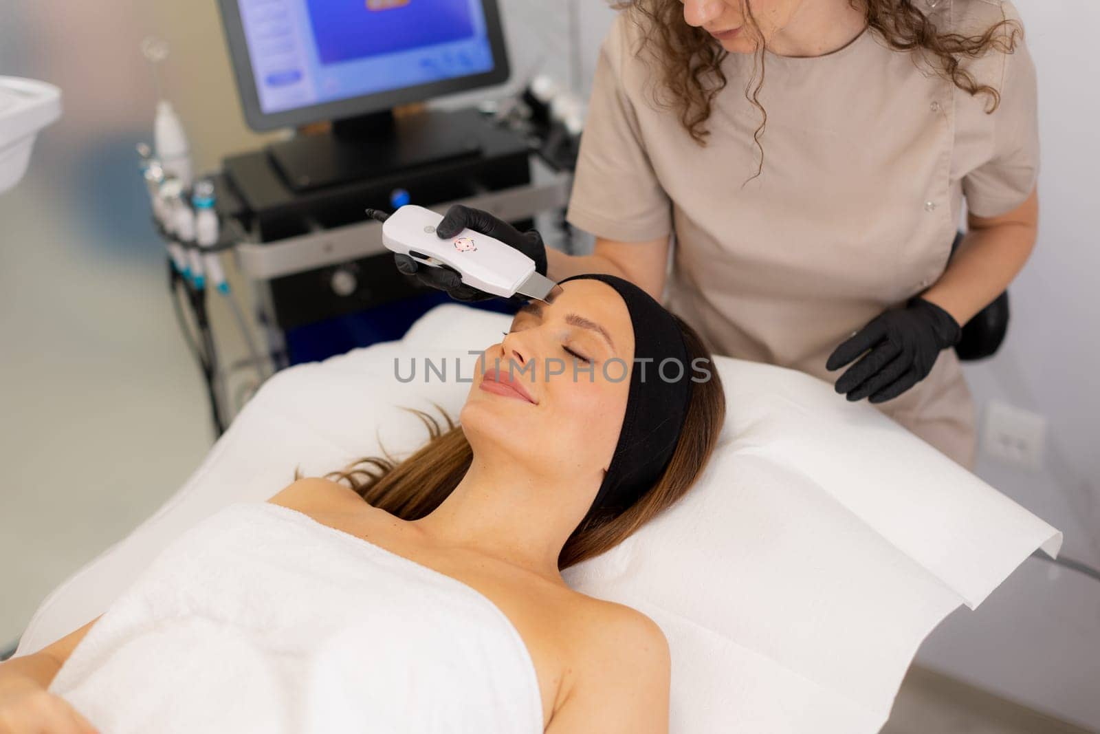 A serene setting showcases a skilled practitioner using an ultrasonic facial massager on a client's skin, promoting deep cleansing and relaxation for a radiant complexion.