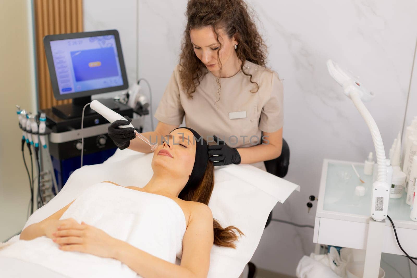 A skilled therapist employs high frequency therapy on a client's face, promoting skin health and relaxation in a tranquil spa environment. The atmosphere radiates comfort and care.