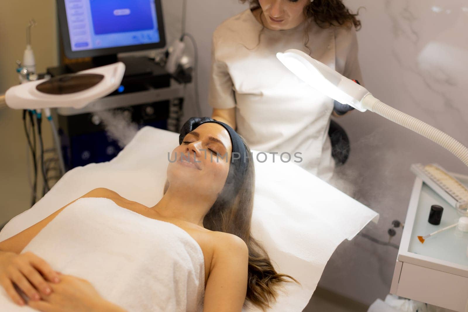 A tranquil spa setting features a woman enjoying a facial treatment, with mist enveloping her face. The atmosphere promotes relaxation and skincare rejuvenation.