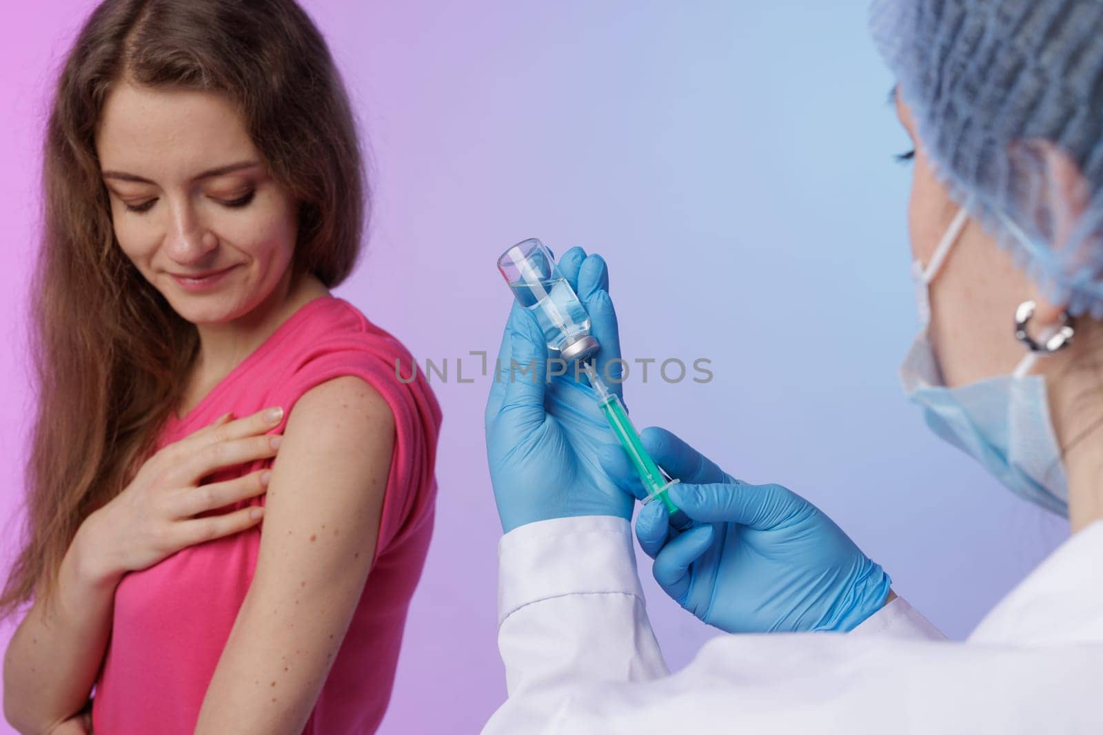 Healthcare professional in blue gloves prepares to administer a vaccine injection to a patient's upper arm using a syringe and vial. concept of modern medicine