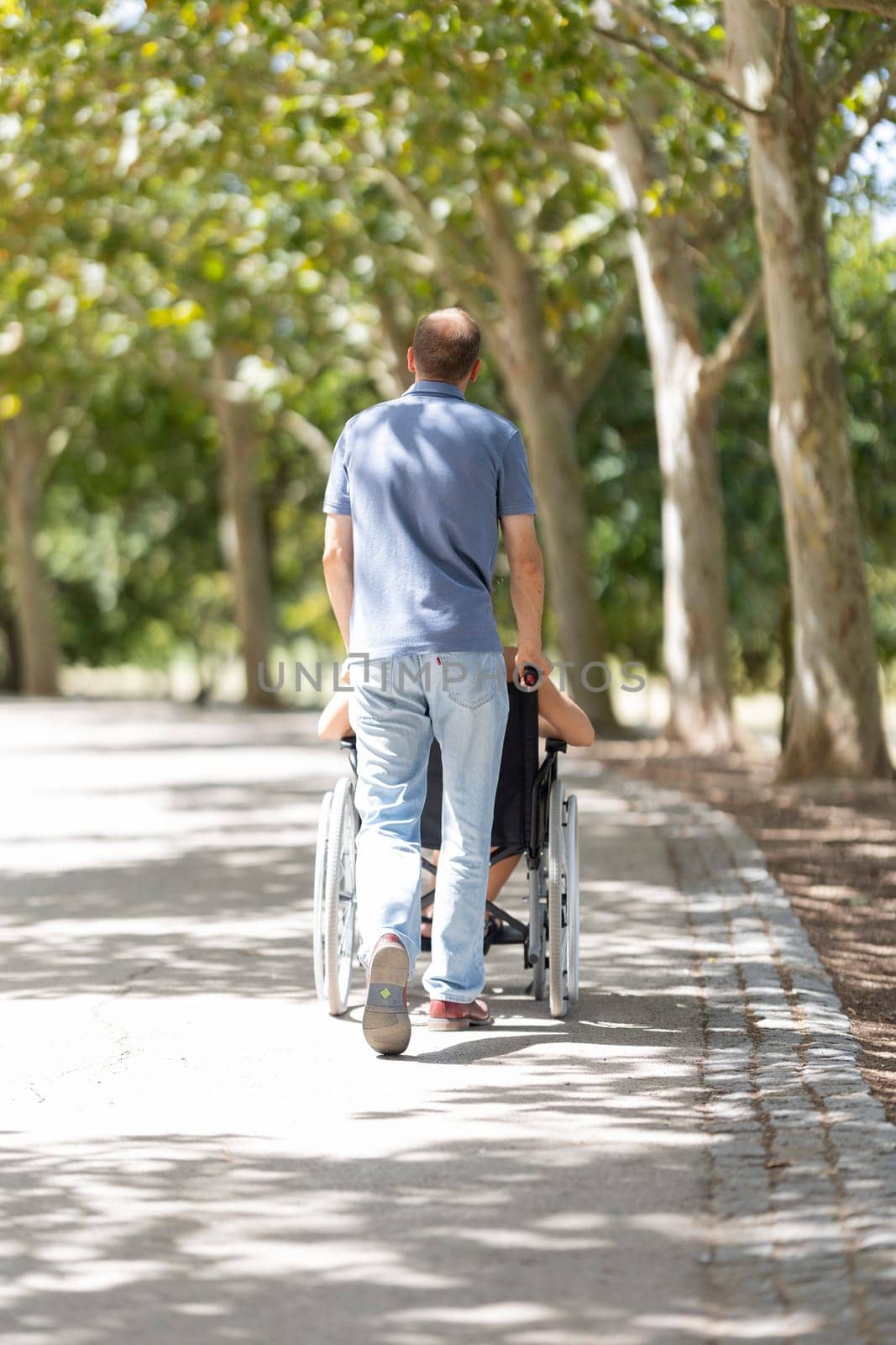Nurse assisting elderly patient in wheelchair enjoying walk in sunny park