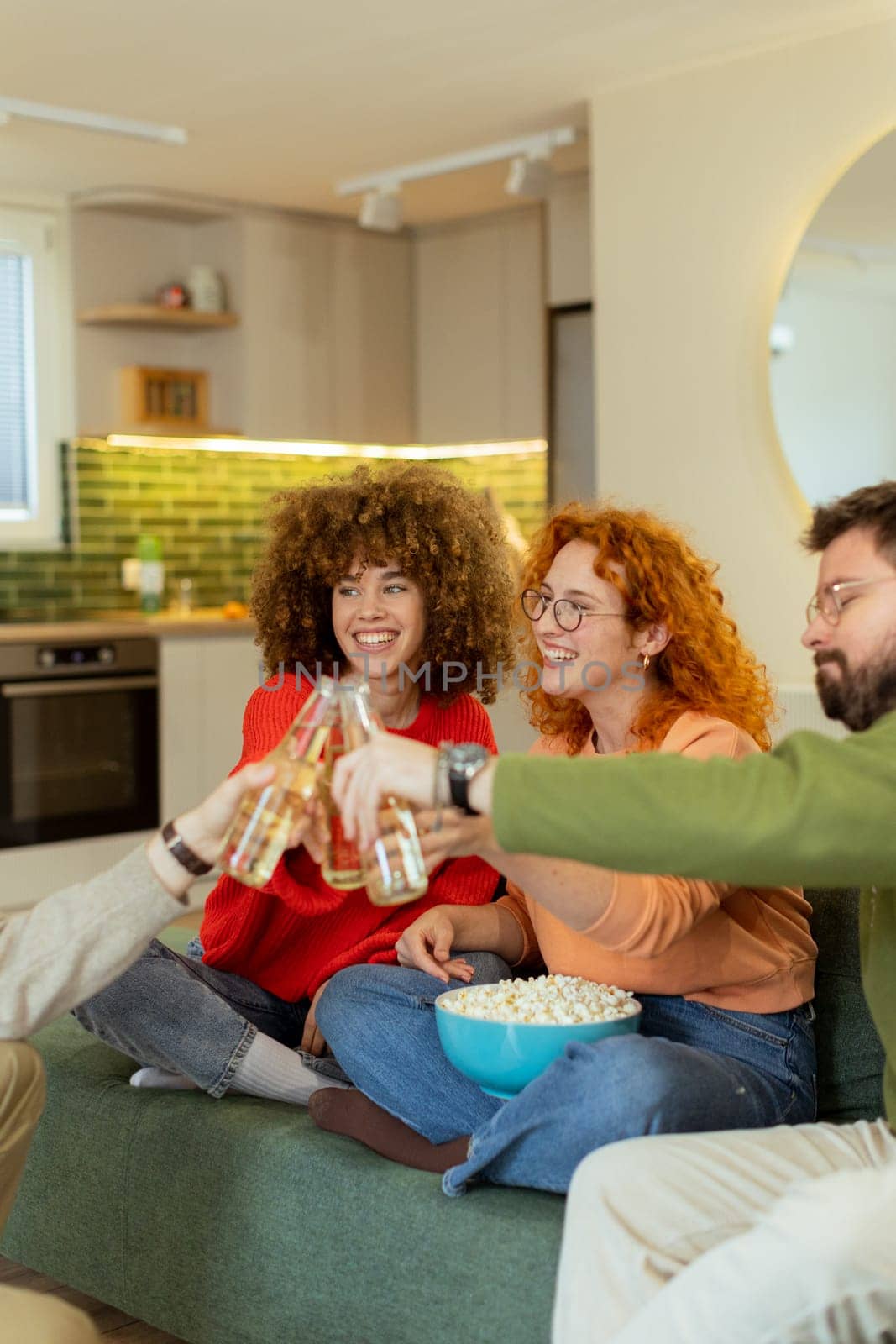 Friends gather in a stylish living room, raising glasses filled with refreshing drinks. They share laughter and warmth while surrounded by a bowl of popcorn, creating joyful memories