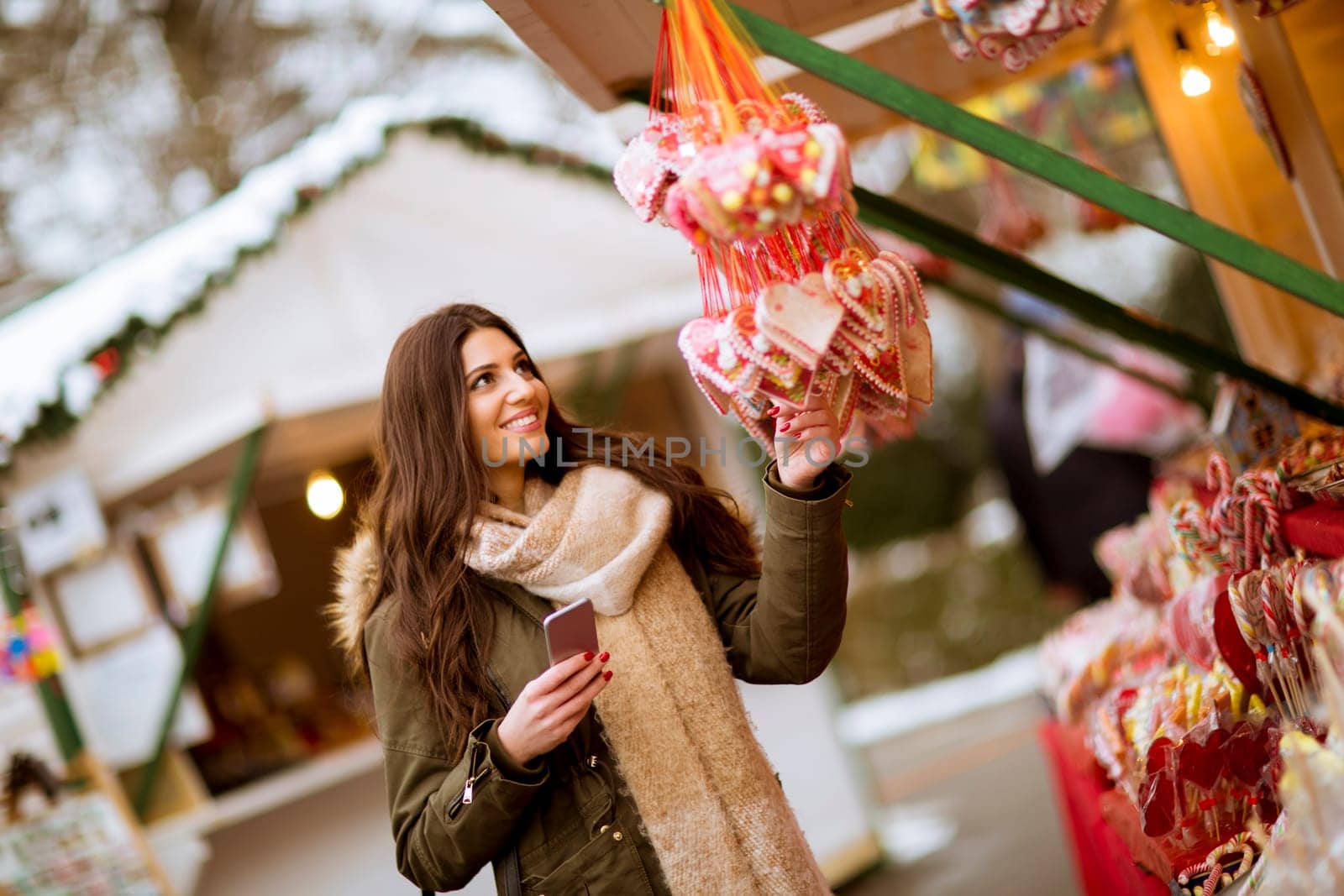 Portrait of smiling young woman using phone in park at cold winter day