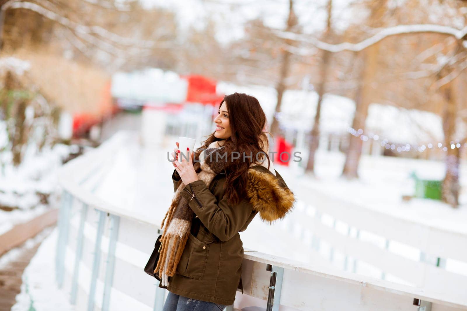 Young woman drinking tea or coffee over winter nature background outdoor