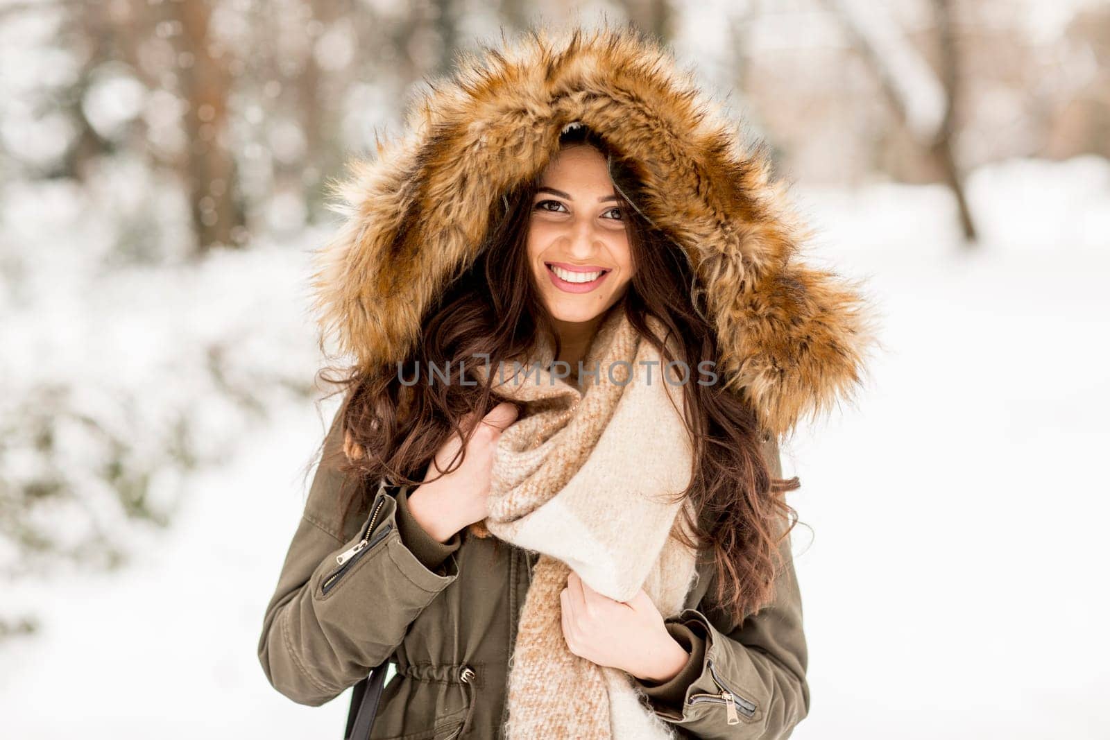 Young woman with a fur hood in the park on the snow