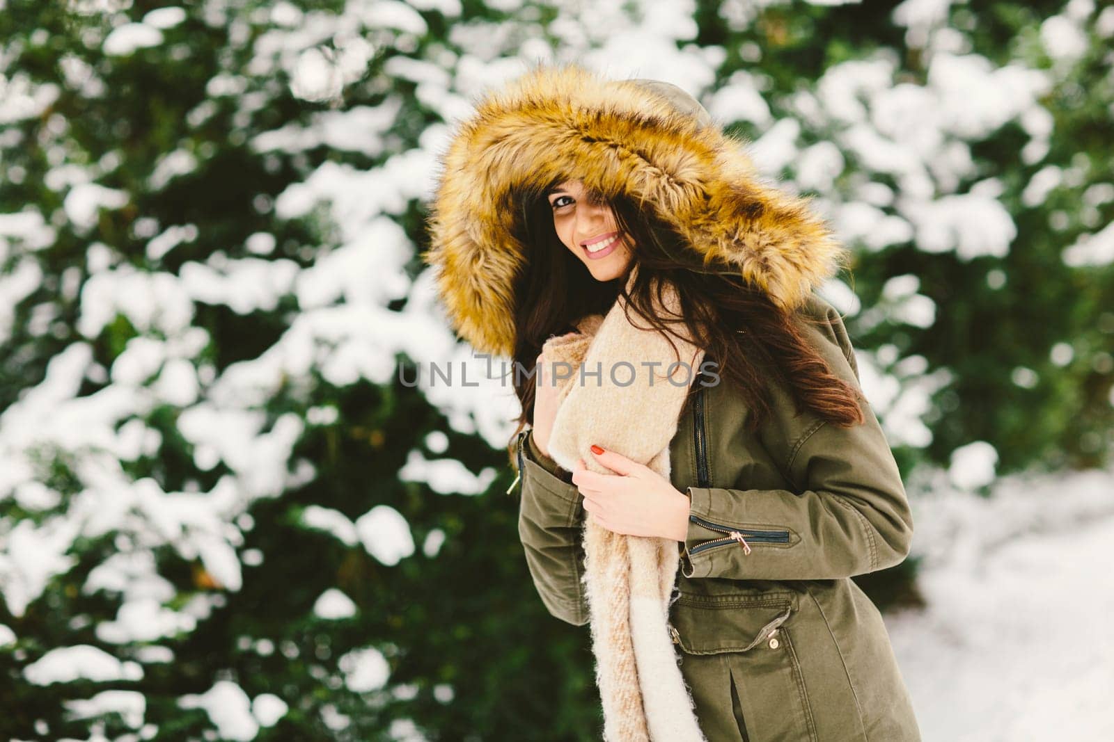 Young woman with a fur hood in the park on the snow