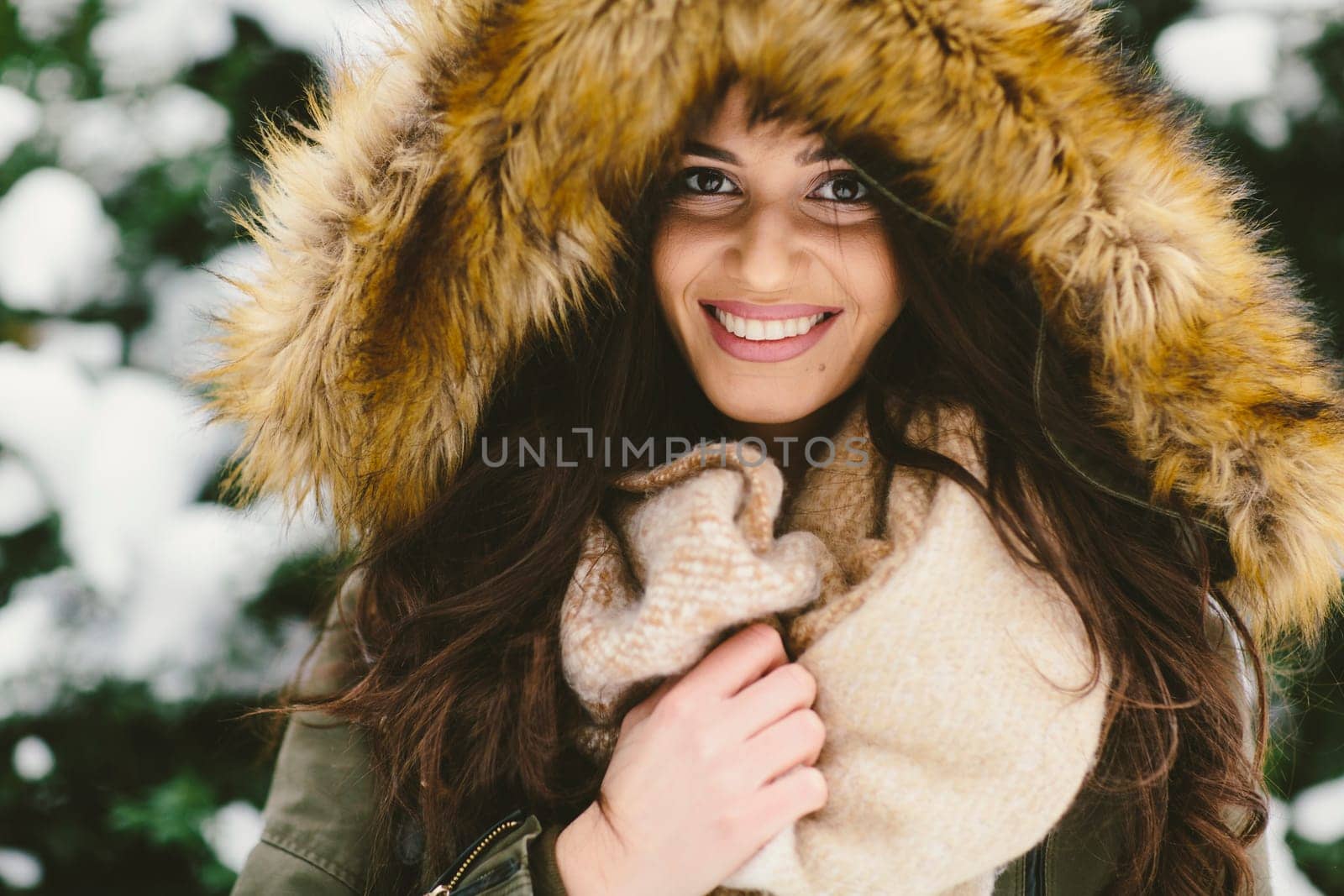 Young woman with a fur hood in the park on the snow
