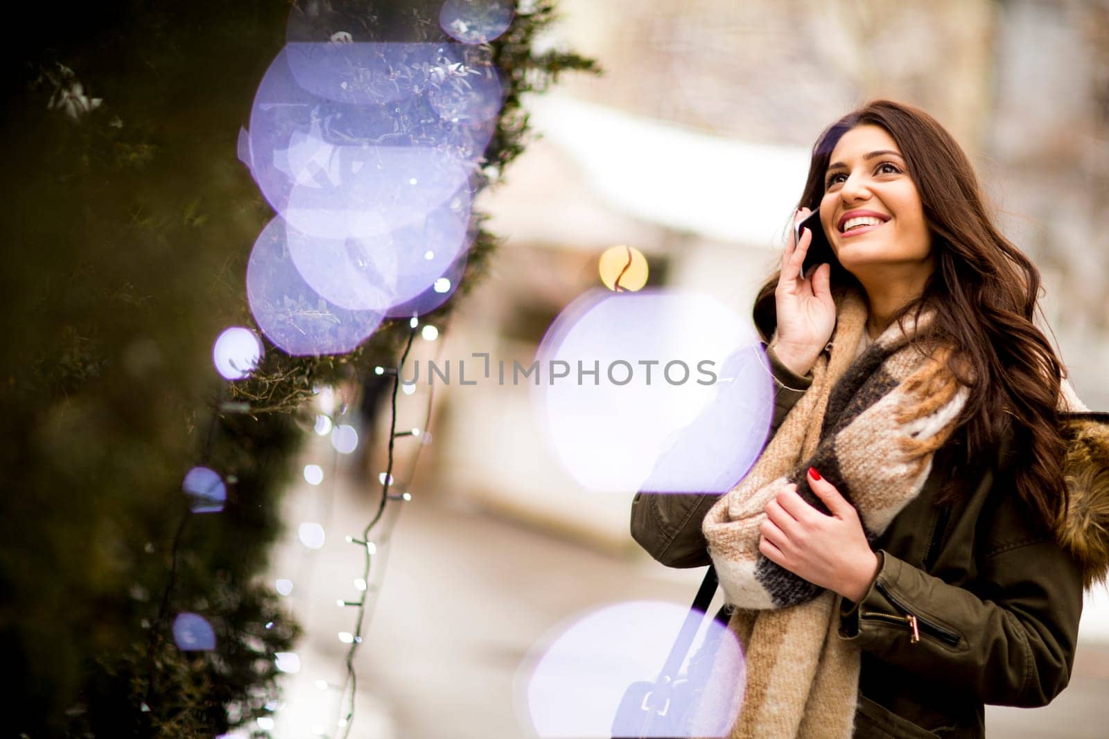 Young woman using a phone in the winter park at Christmas market