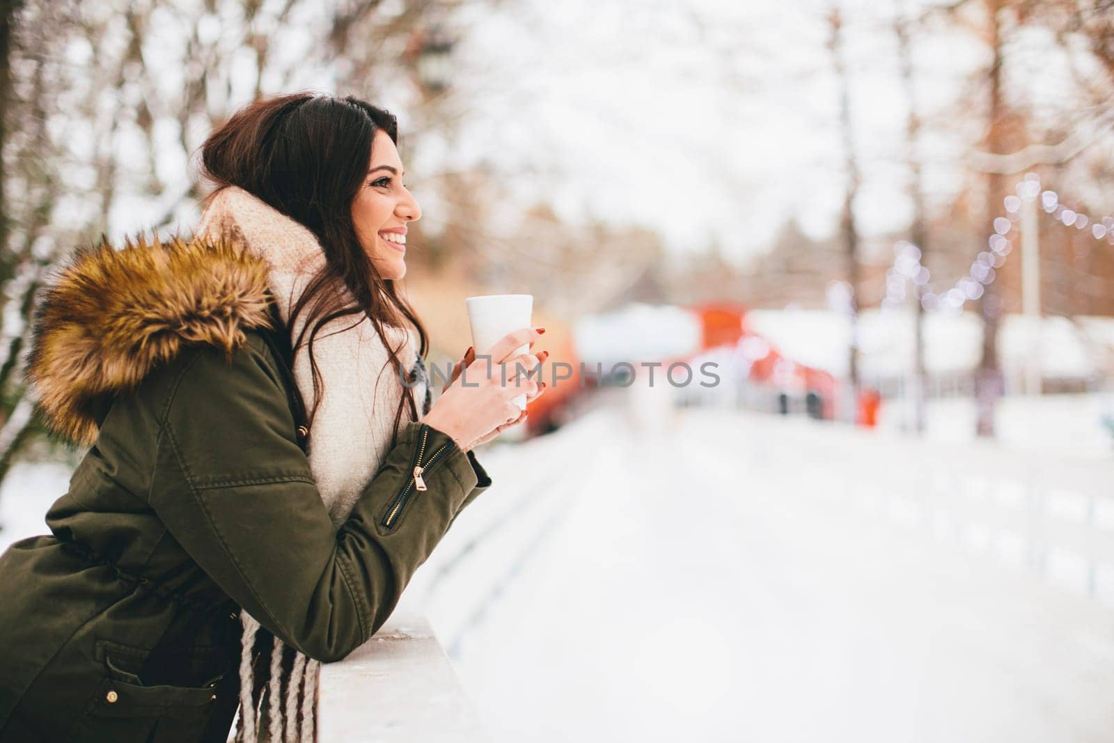 Happy woman with a cup of hot drink on  cold winter outdoors