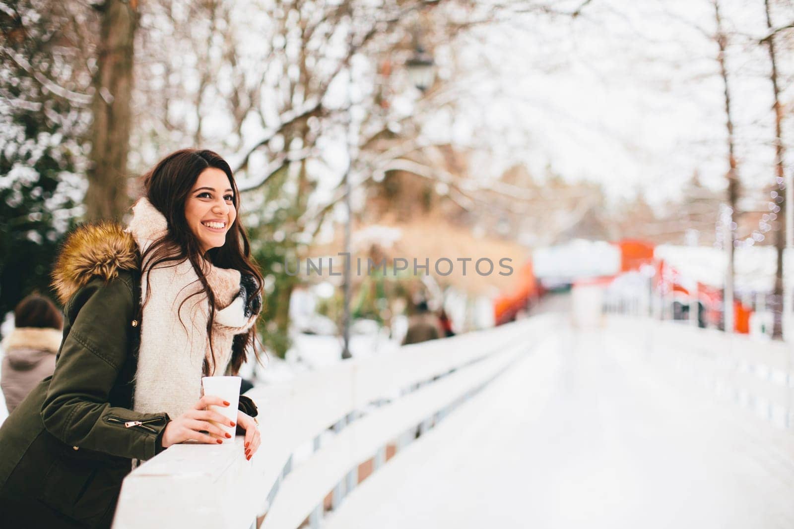 Happy woman with a cup of hot drink on  cold winter outdoors