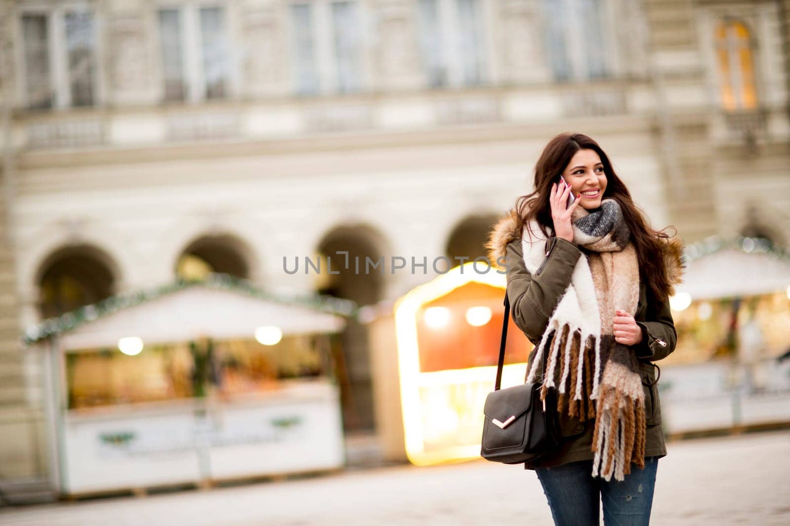 Happy fashion woman using a smart phone on street in winter