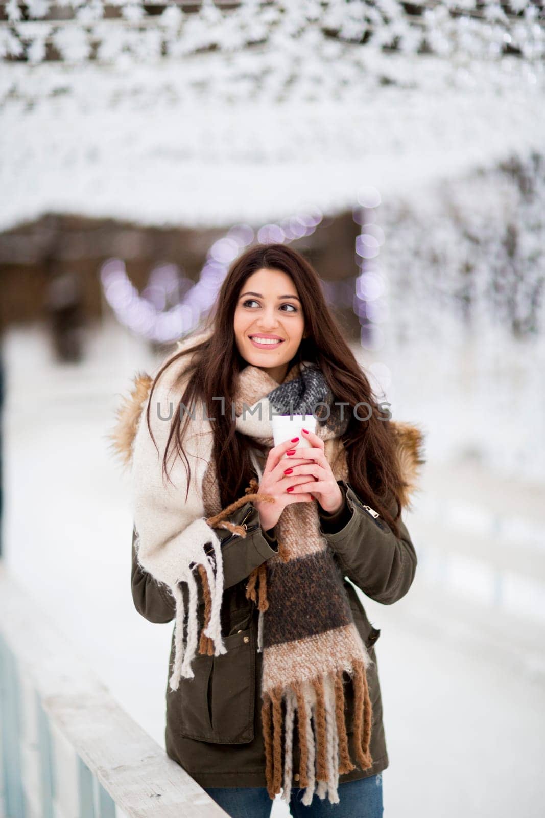 Happy woman with a cup of hot drink on  cold winter outdoors