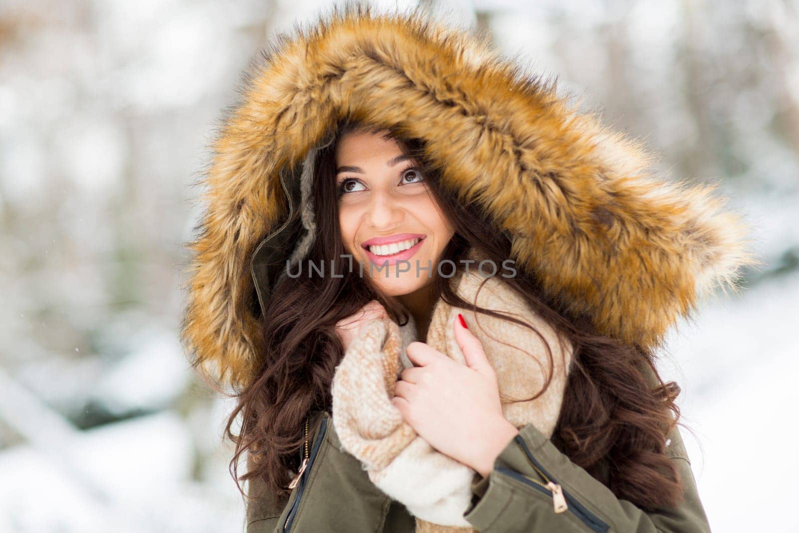 Pretty young woman with hood in the park on the winter day