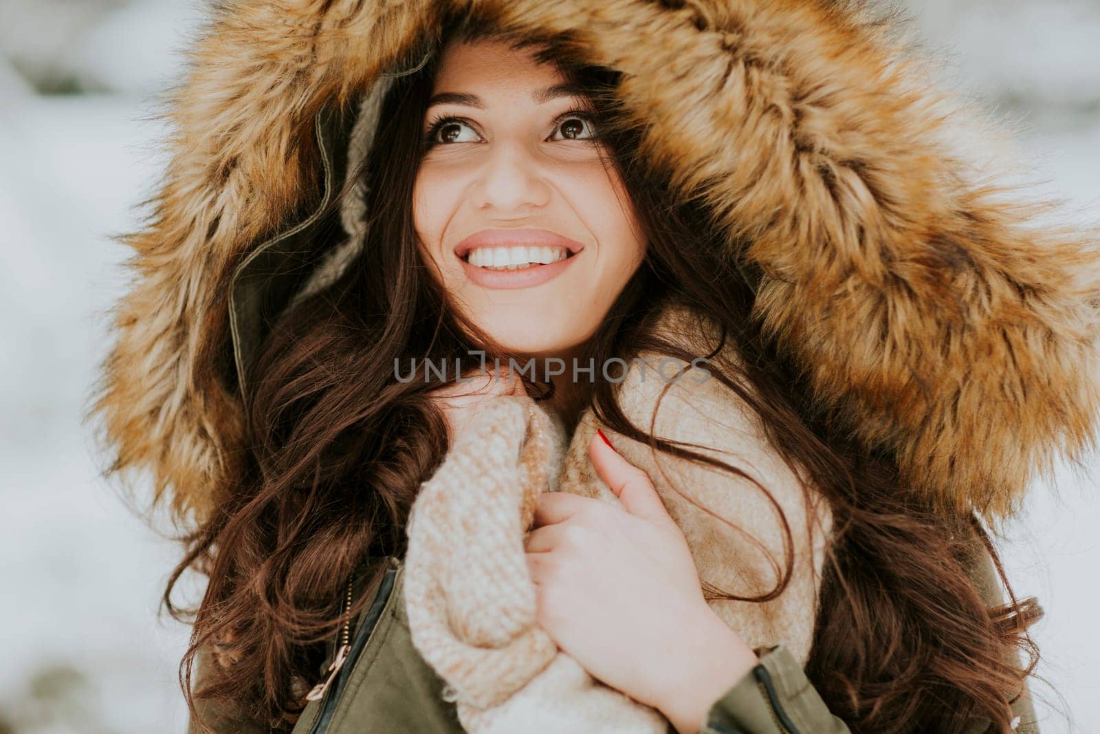 Pretty young woman with hood in the park on the winter day