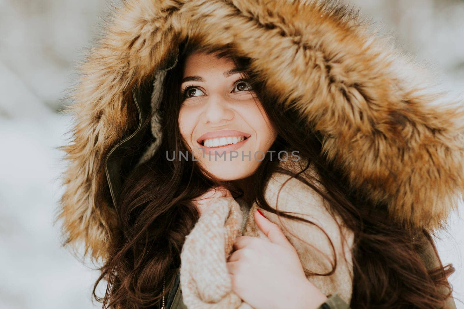 Pretty young woman with hood in the park on the winter day