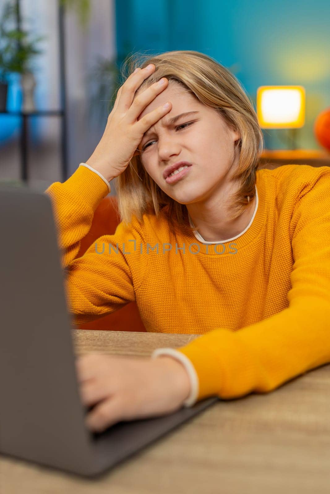 Caucasian teenager boy frustrated while playing a difficult video game on laptop at home. Irritated banging on keyboard, upset about losing sitting on couch by table, expressing anger disappointment