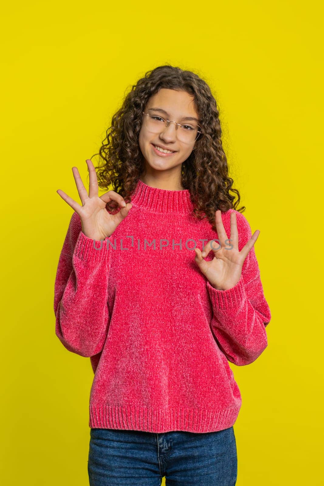 Okay. Happy Caucasian young teenager girl looking approvingly at camera showing ok gesture, like sign positive feedback, approve something good, celebrate victory. Teen child kid on yellow background
