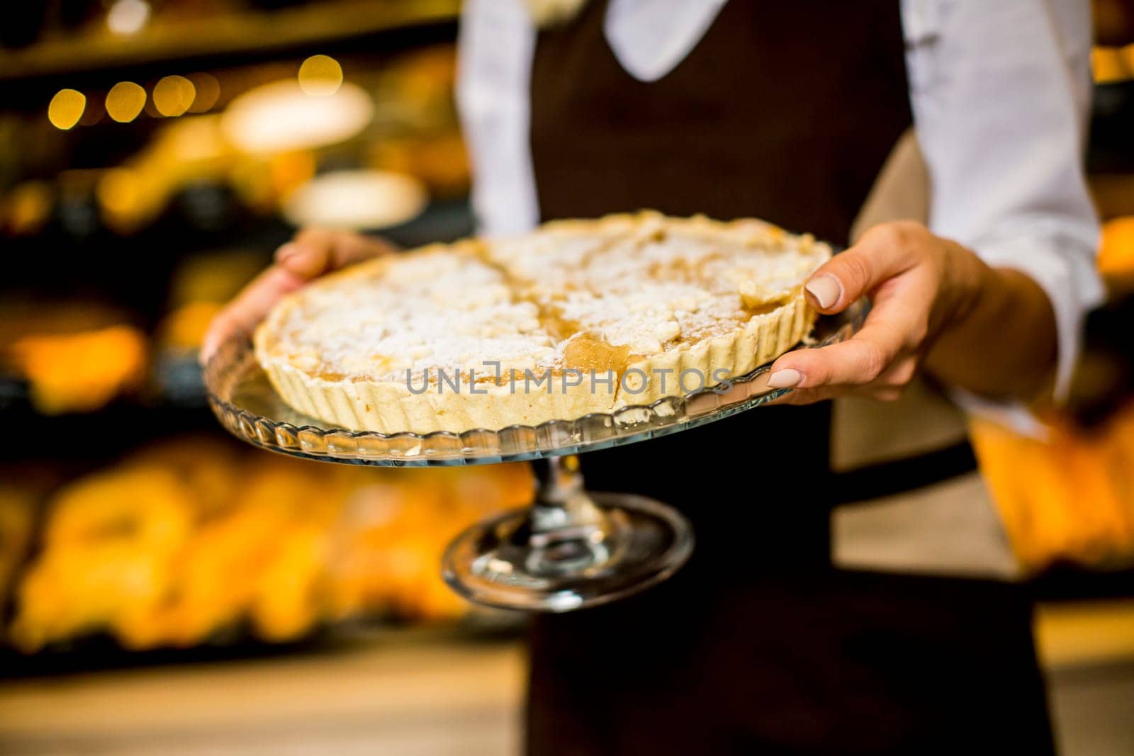 Bakery female worker posing with apple tart in bakery