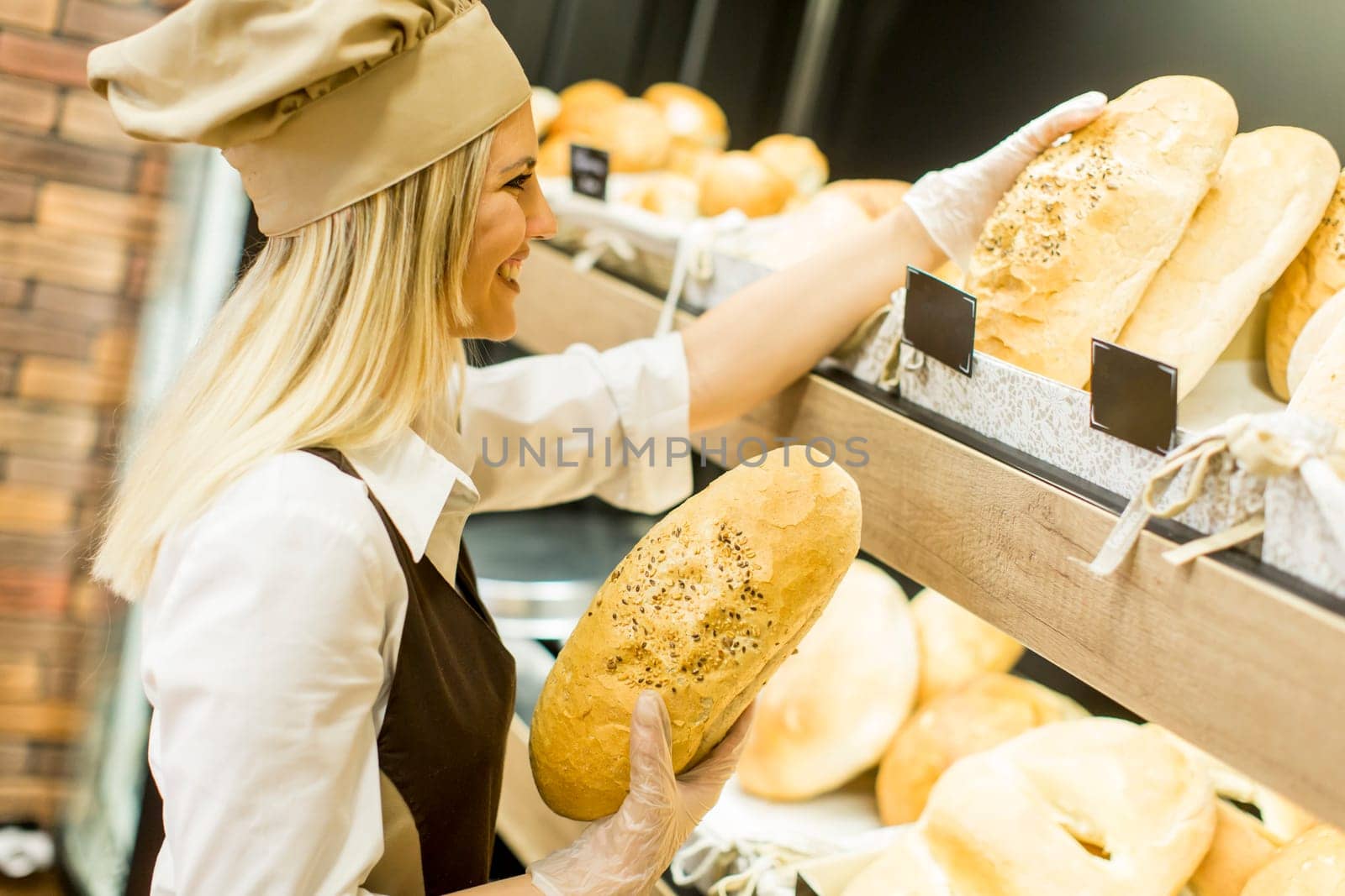 Pretty young woman selling fresh bread in the bakery