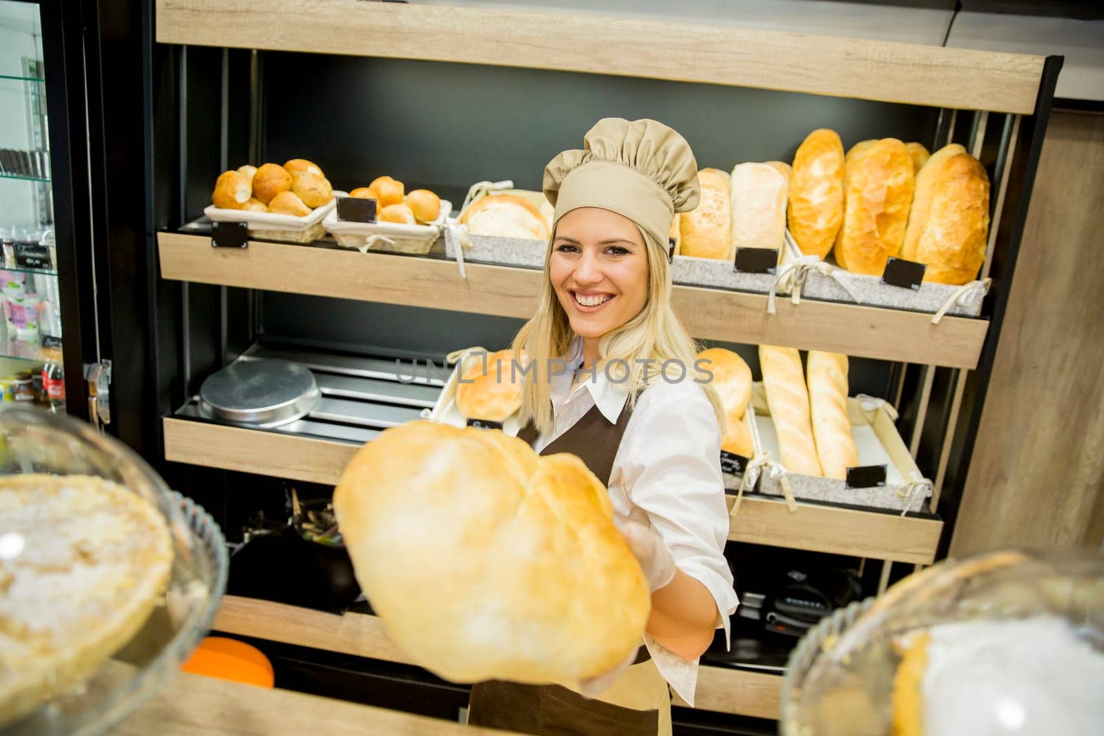 Pretty young woman selling fresh bread in the bakery