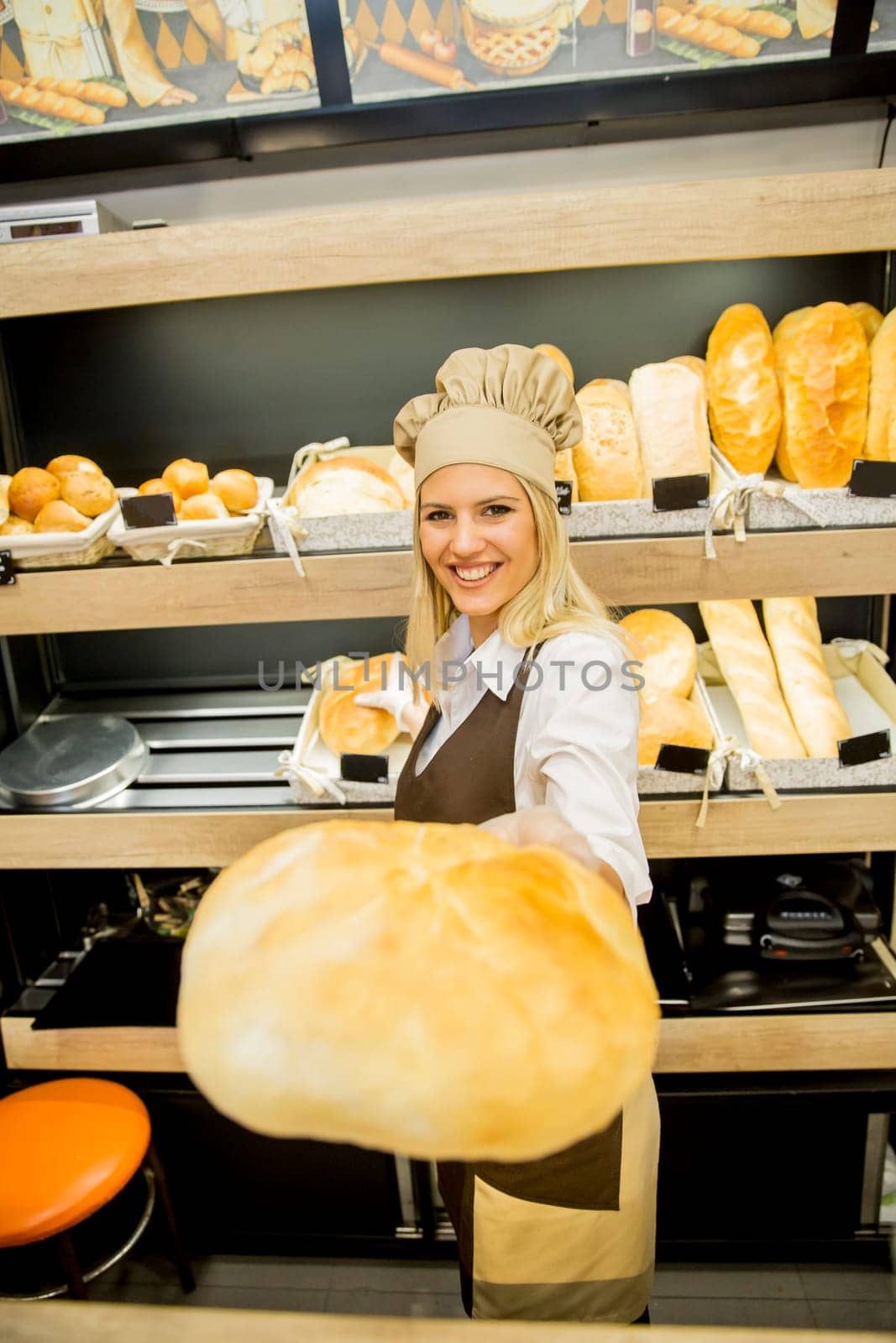 Pretty young woman selling fresh bread in the bakery