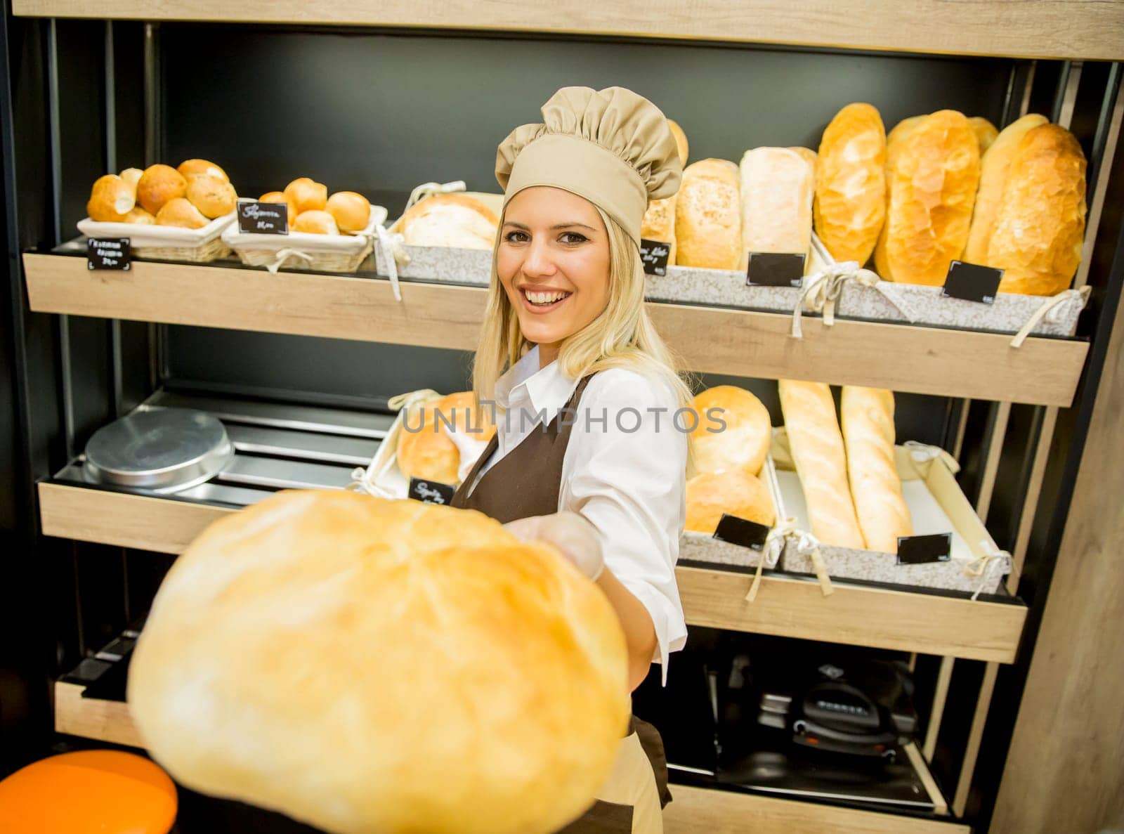 Pretty young woman selling fresh bread in the bakery