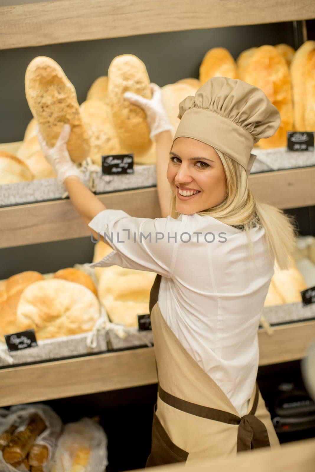 Pretty young woman selling fresh bread in the bakery