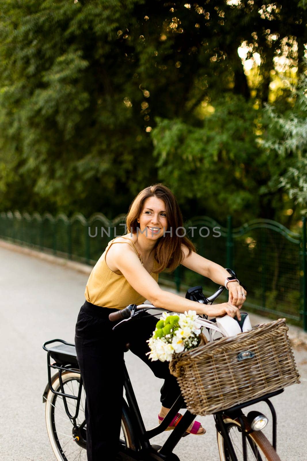 Joyful woman with flowers in the basket of electric bike